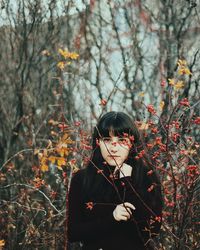 Portrait of young woman standing by flowers in forest