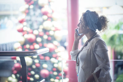 Side view of woman talking on phone indoors