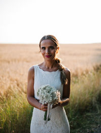 Portrait of a smiling young woman standing on field