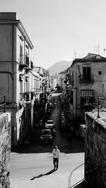 Rear view of man walking on street amidst buildings in city