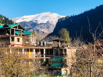 Built structure by trees and houses against sky during winter