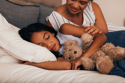 Midsection of woman sleeping on bed at home