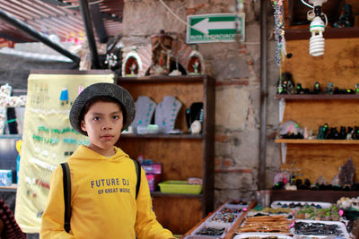 Portrait of boy standing at store in city