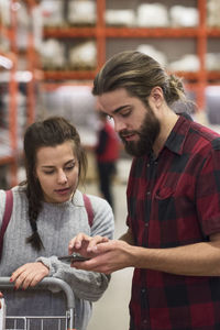 Couple using smart phone while shopping in hardware store