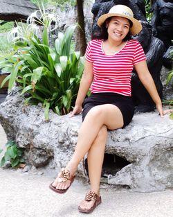 Portrait of smiling woman sitting against stone wall