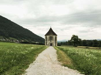 Scenic view of land by building against sky