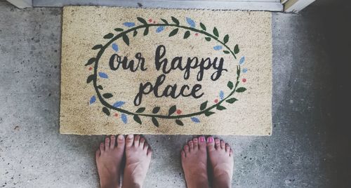 Low section of man and woman standing in front of doormat with text