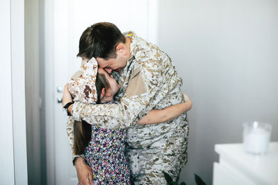 Father kissing daughter at home