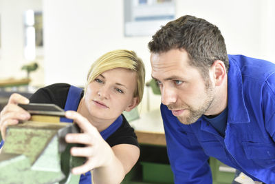 Instructor examining workpiece of trainee