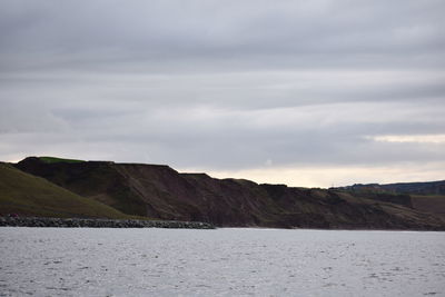 Scenic view of sea and mountains against sky