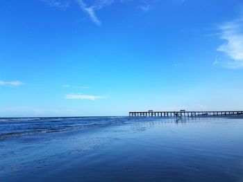 Pier over sea against blue sky