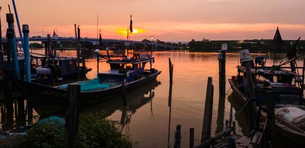 Boats moored at harbor during sunset