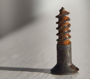 Close-up of metallic object on table against wall