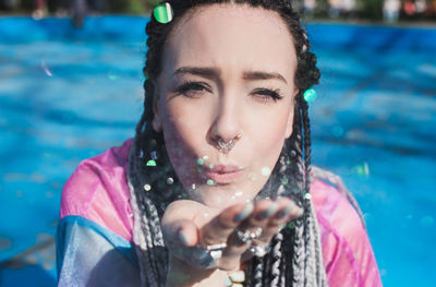 Portrait of smiling young woman blowing glitters