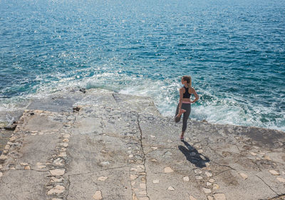 Woman running training on sea coastline under sunlight in sunny summer day. sport, run, health.