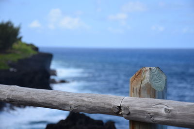 Close-up of wooden post by sea against sky