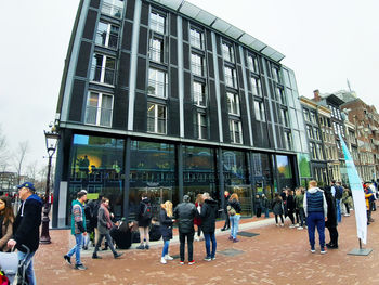 People walking on modern building in city against sky