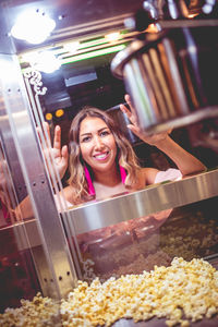 Smiling woman standing by popcorn maker