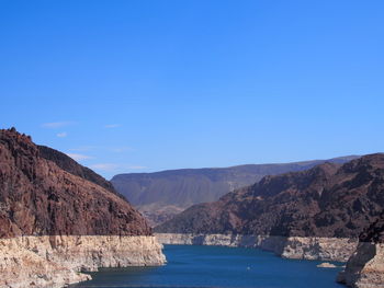 Scenic view of sea and mountains against clear blue sky