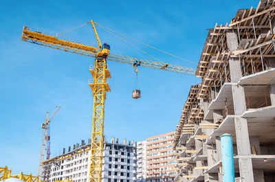 Construction of multi-storey building.yellow and blue cranes. cargo transfer.