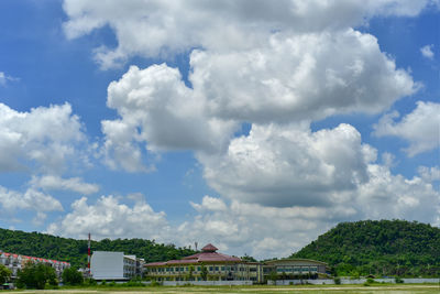 Houses and trees by building against sky