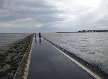 Pier on sea against cloudy sky