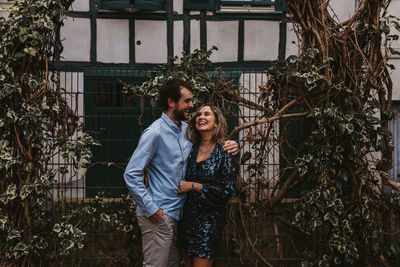 Content young man and woman hugging and kissing while standing near metal fence on city street and enjoying summer day together