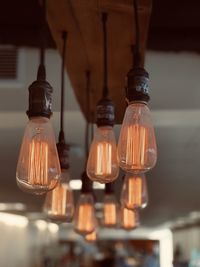 Close-up of illuminated light bulb hanging at ceiling