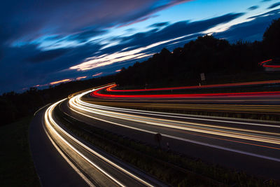 Light trails on road against sky at night