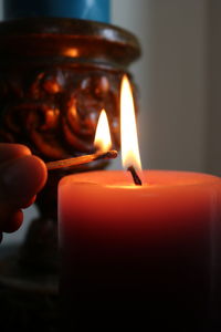 Close-up of human hand burning candle