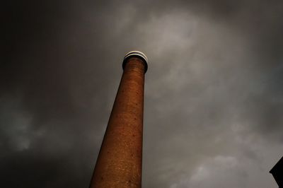 Low angle view of smoke stack against cloudy sky