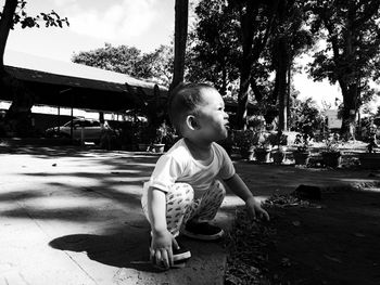 Full length of cute boy crouching in park