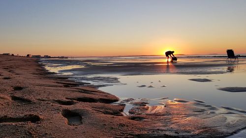 People on beach against sky during sunset