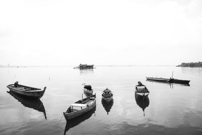 Boats moored in sea against clear sky