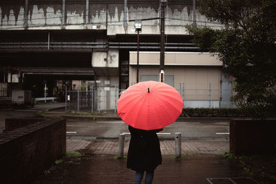 Rear view of woman walking on wet street in city during rainy season