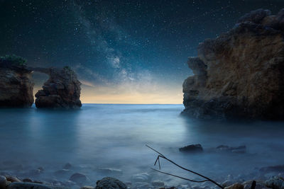 Rock formation in sea against sky at night