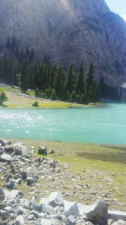 water, tranquil scene, tranquility, scenics, beauty in nature, rock - object, nature, mountain, tree, lake, stone - object, sky, non-urban scene, idyllic, landscape, day, river, remote, lakeshore, rock