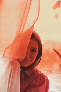 Portrait of a beautiful young woman standing against orange sky