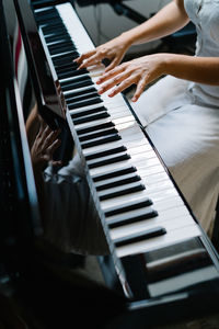 Crop anonymous female musician playing piano while practicing at home at weekend