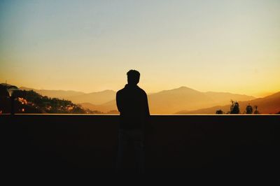 Silhouette man looking at mountain against sky during sunset