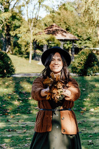 Young woman wearing hat standing against trees