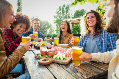 Smiling friends toasting drinks on table