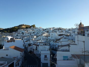 High angle view of houses in town against clear blue sky