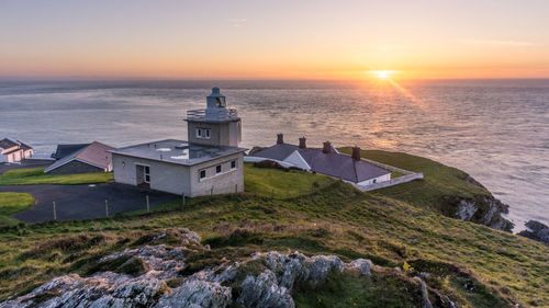 Scenic view of sea by buildings against sky during sunset