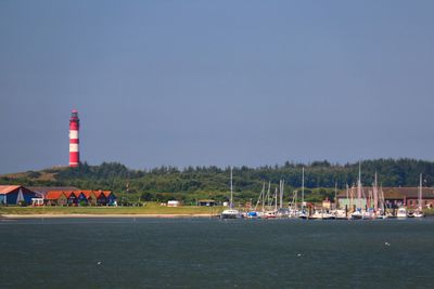 Lighthouse by sea against clear sky