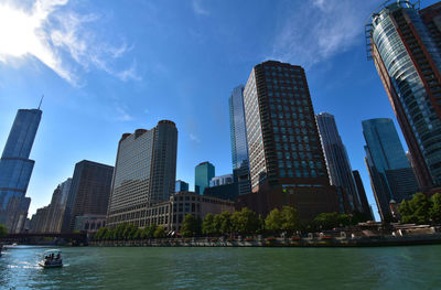 Skyscrapers by modern buildings in city against sky
