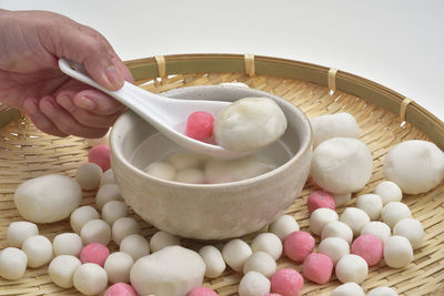 Cropped hand of man holding food in bowl over white background