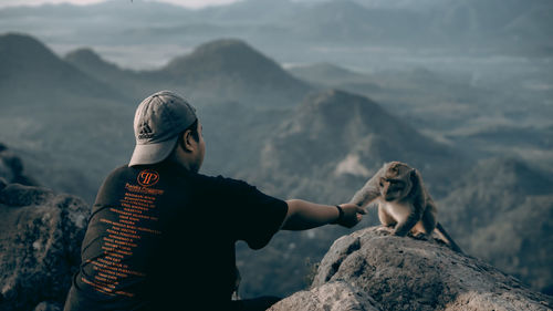 Rear view of man on rock against mountains