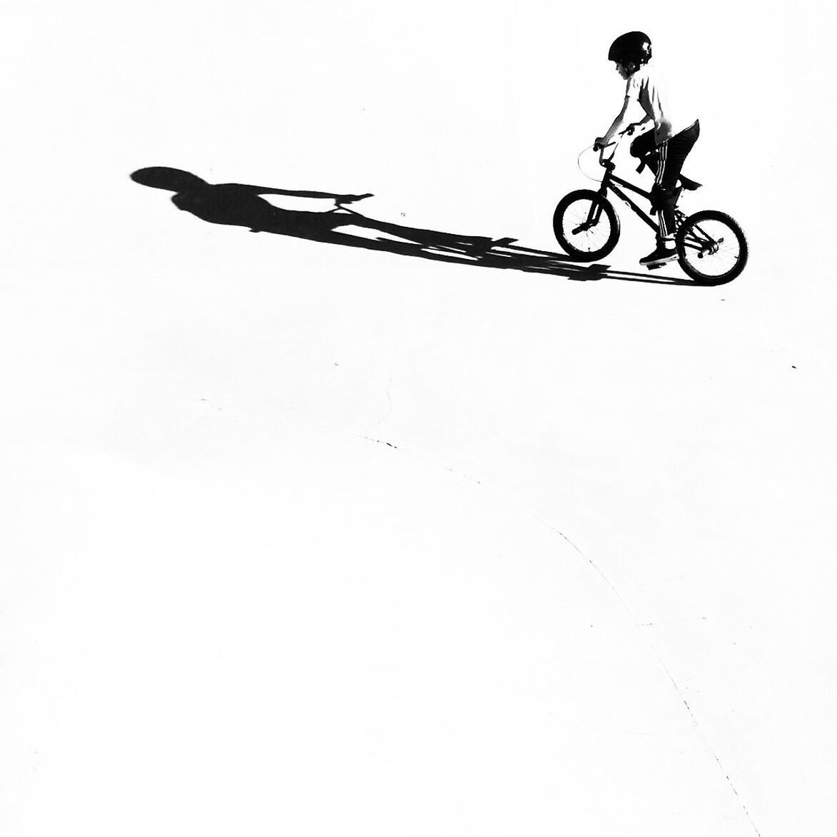 MAN RIDING BICYCLE ON WHITE WALL