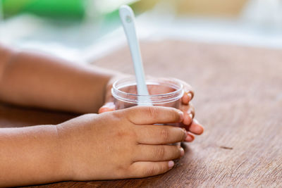 Close-up of hand holding drink drinking glass on table